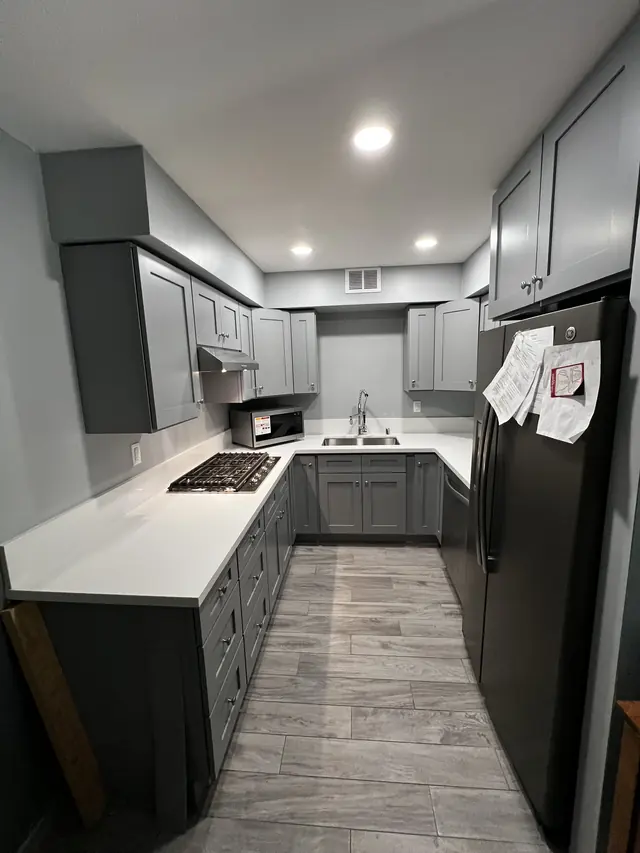 Grey shaker galley kitchen with a gas cooktop and white quartz counters