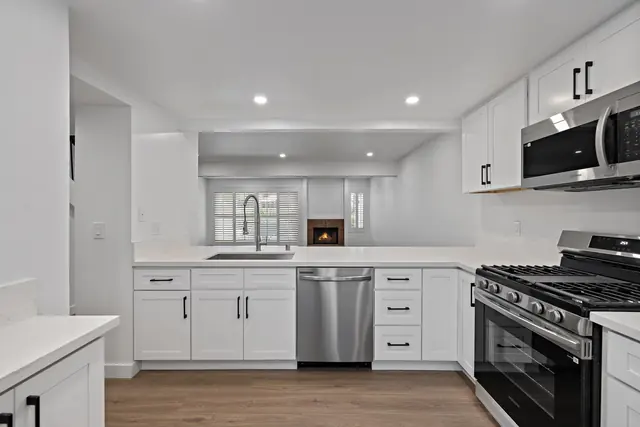 White shaker kitchen opened up to the living room, with recessed lighting