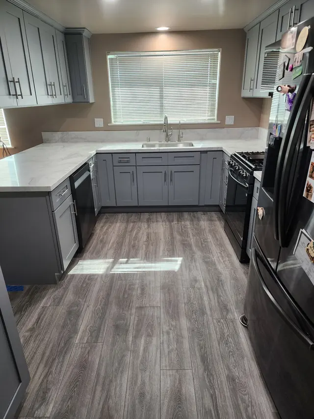 Grey shaker U-shaped kitchen with marble-look quartz counters and a window over the sink